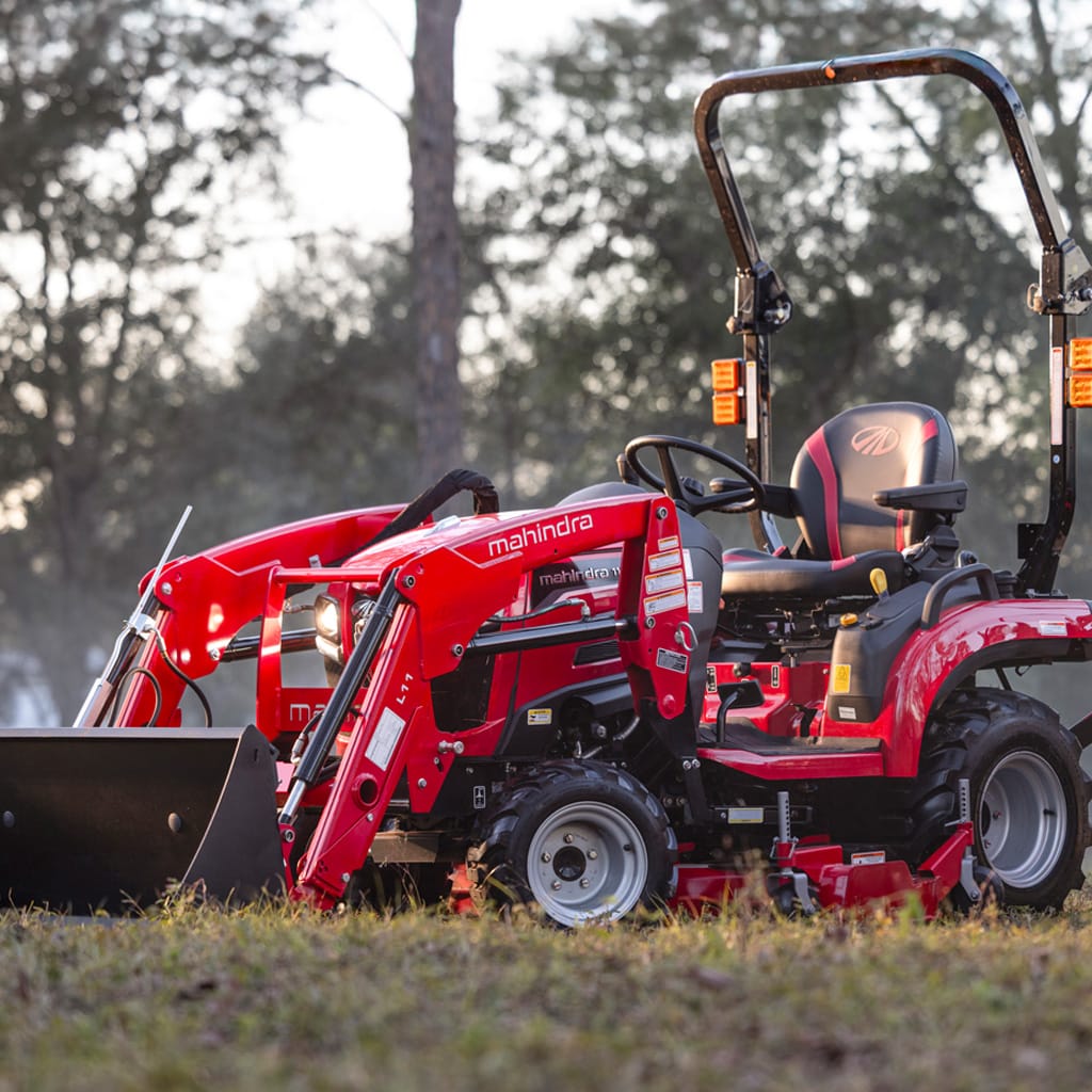 Tracteur sous-compact Mahindra 1120 rouge devant une forêt